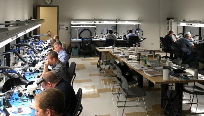 Technicians practicing soldering at microscope benches in a CTTi training classroom